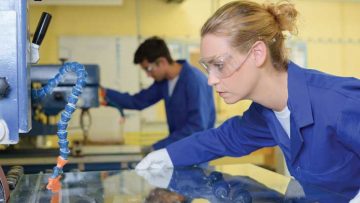 Woman-holding-sheet-glass-under-machine