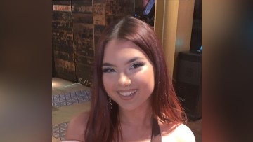 A young woman with long, red hair smiles toward the camera.