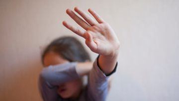 Child holding up hand and covering face