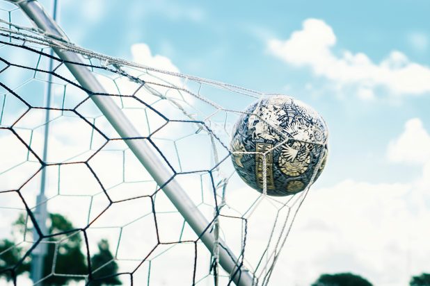 Football in motion in a goal net